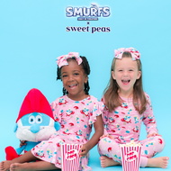 Two children in pink 'Smurfs' themed pajamas with a Smurf character on a blue background.