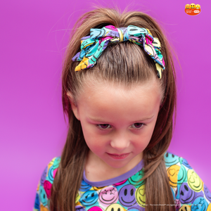 Young girl with a colorful hair bow against a purple background