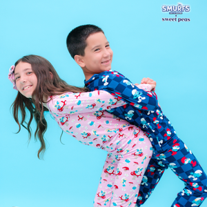 Two children in colorful pajamas hugging on a blue background with 'Smurfs' branding.