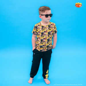 Child wearing a colorful shirt with vehicle patterns and black pants on a blue background