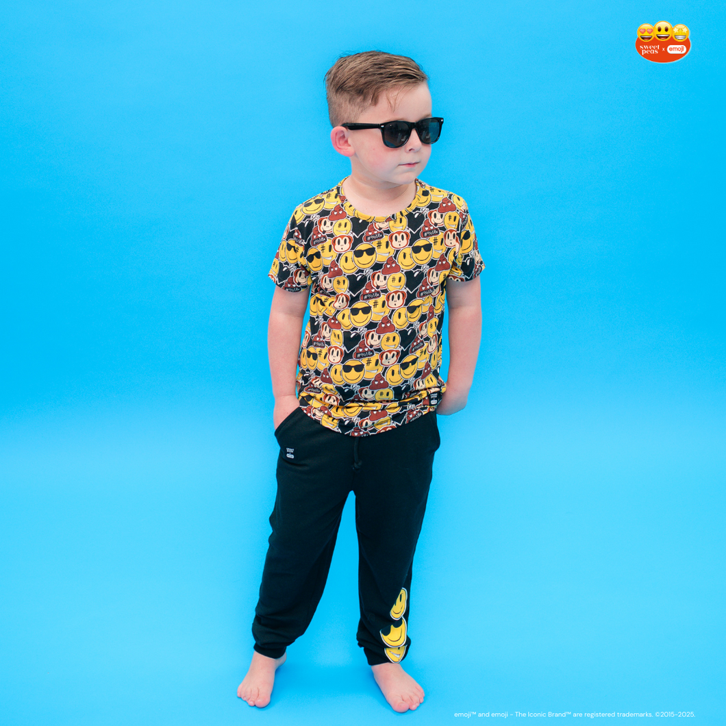 Child wearing a colorful shirt with vehicle patterns and black pants on a blue background