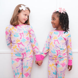 Two children wearing colorful pajamas with butterfly patterns against a white background.