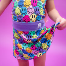 Load image into Gallery viewer, Colorful smiley face swimsuit with a purple waistband on a pink background