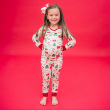 Load image into Gallery viewer, Child wearing a festive pajama set on a red background