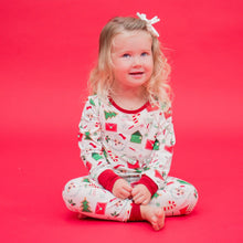 Load image into Gallery viewer, Child wearing a festive pajama set on a red background