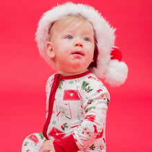 Load image into Gallery viewer, Baby wearing a Santa hat and pajamas on a red background