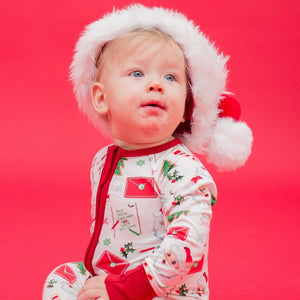 Baby wearing a Santa hat and pajamas on a red background