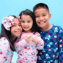 Load image into Gallery viewer, Three children wearing colorful pajamas against a blue background