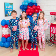Load image into Gallery viewer, Children in Smurfs pajamas standing in a room decorated with balloons and party supplies.