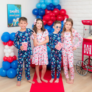 Children in Smurfs pajamas standing in a room decorated with balloons and party supplies.