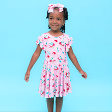 Load image into Gallery viewer, Young girl in a pink Smurfs Official  dress with a floral pattern against a blue background