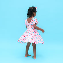 Load image into Gallery viewer, Young girl in a Smurfs pink dress with white patterns on a blue background