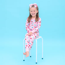 Load image into Gallery viewer, Young girl in Smurfs  pink pajamas sitting on a stool against a blue background